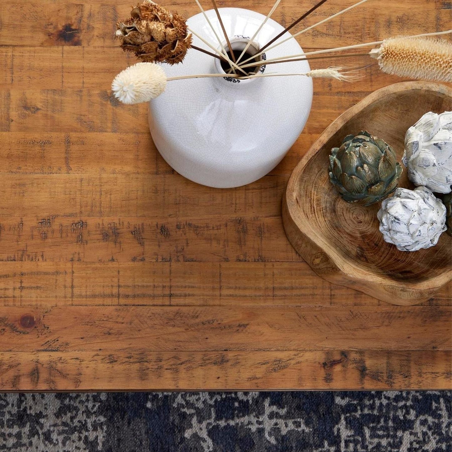 antique bronze artichoke, with stone effect artichokes in wooden trinket dish. Next to white distressed vase with dried grasses in. Taken as birds eye view