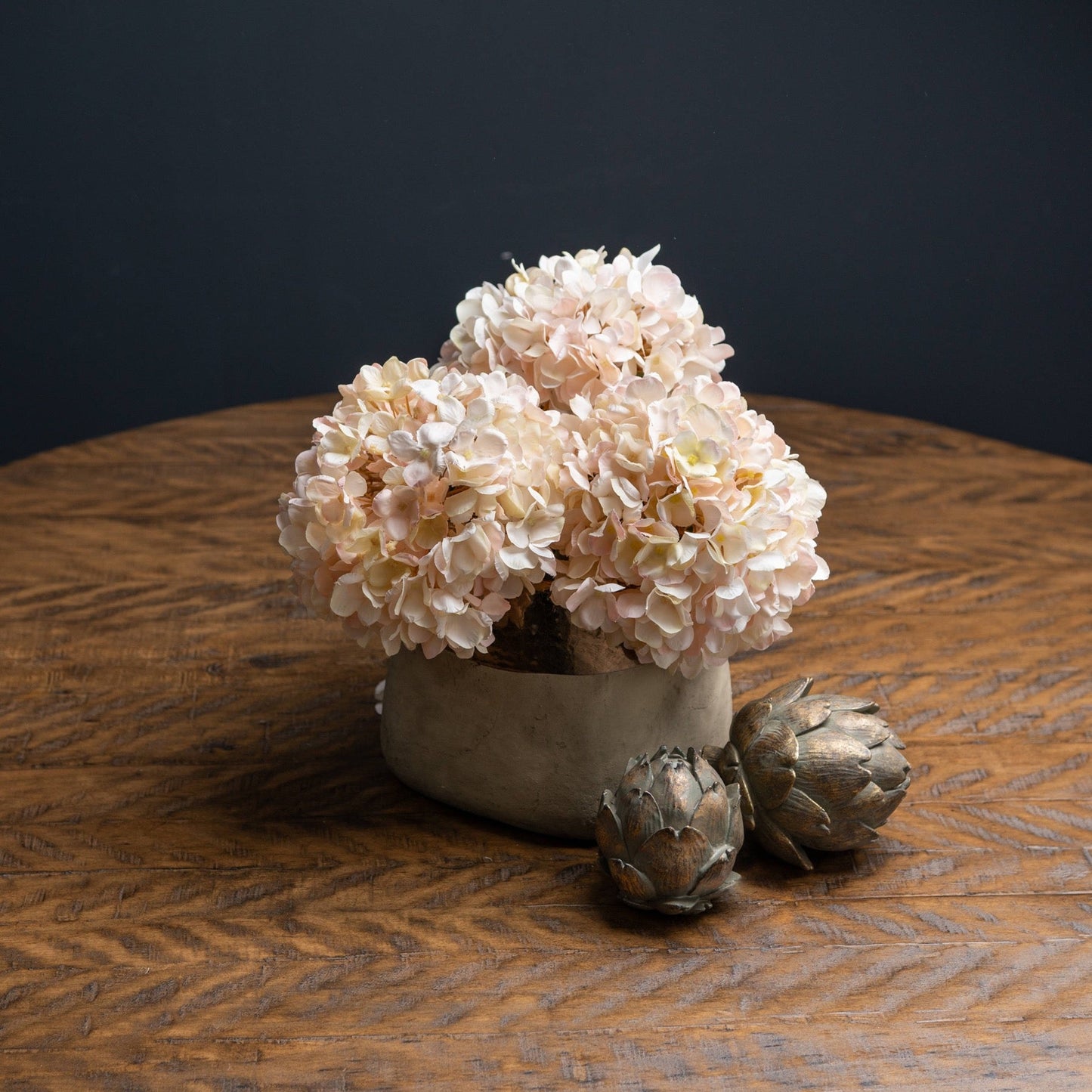 Autumn White Hydrangea's cut short to fit in stone vase. Two bronze artichokes to the front