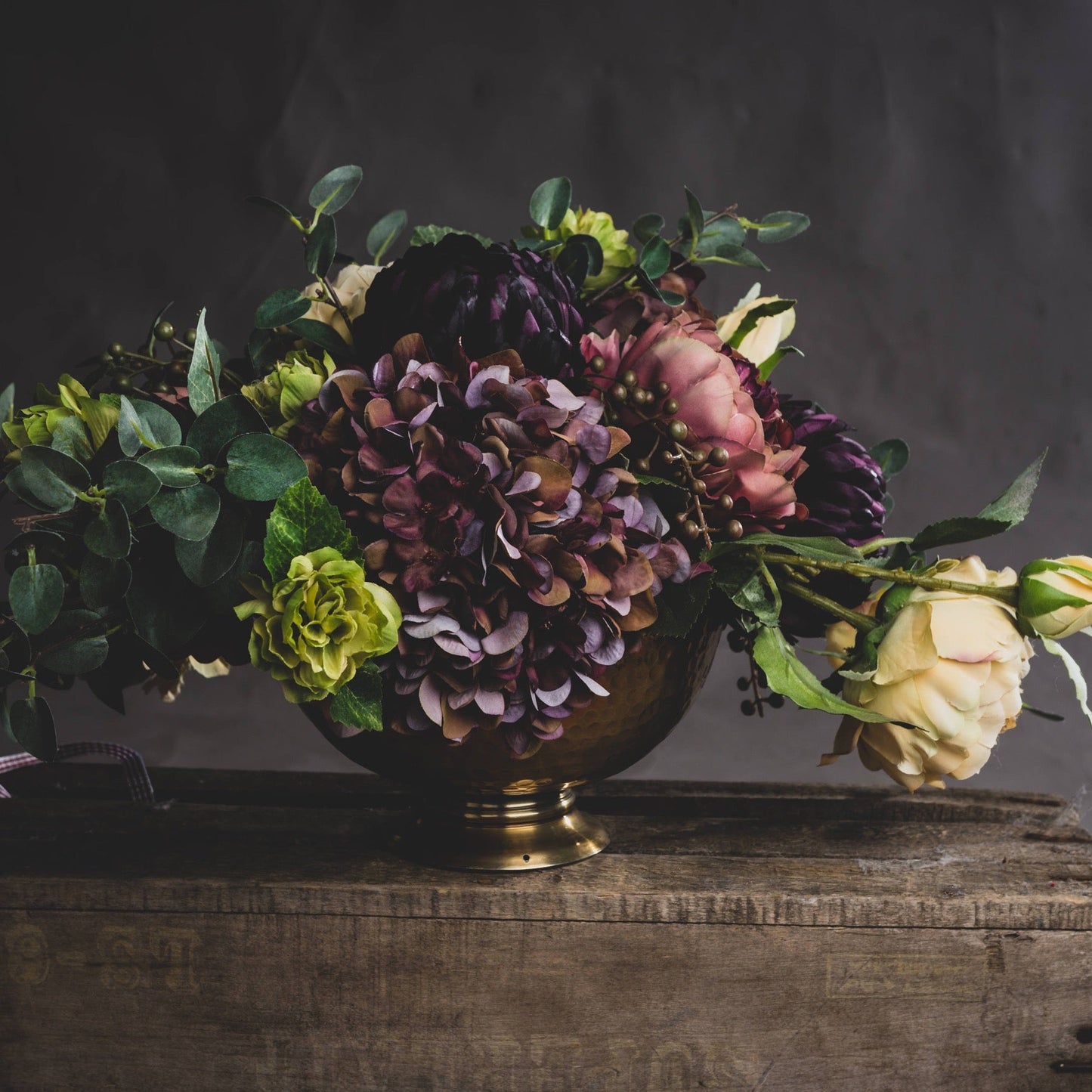 floral display comprising of burgundy hydrangea with other autumn florals in gold bucket style vase