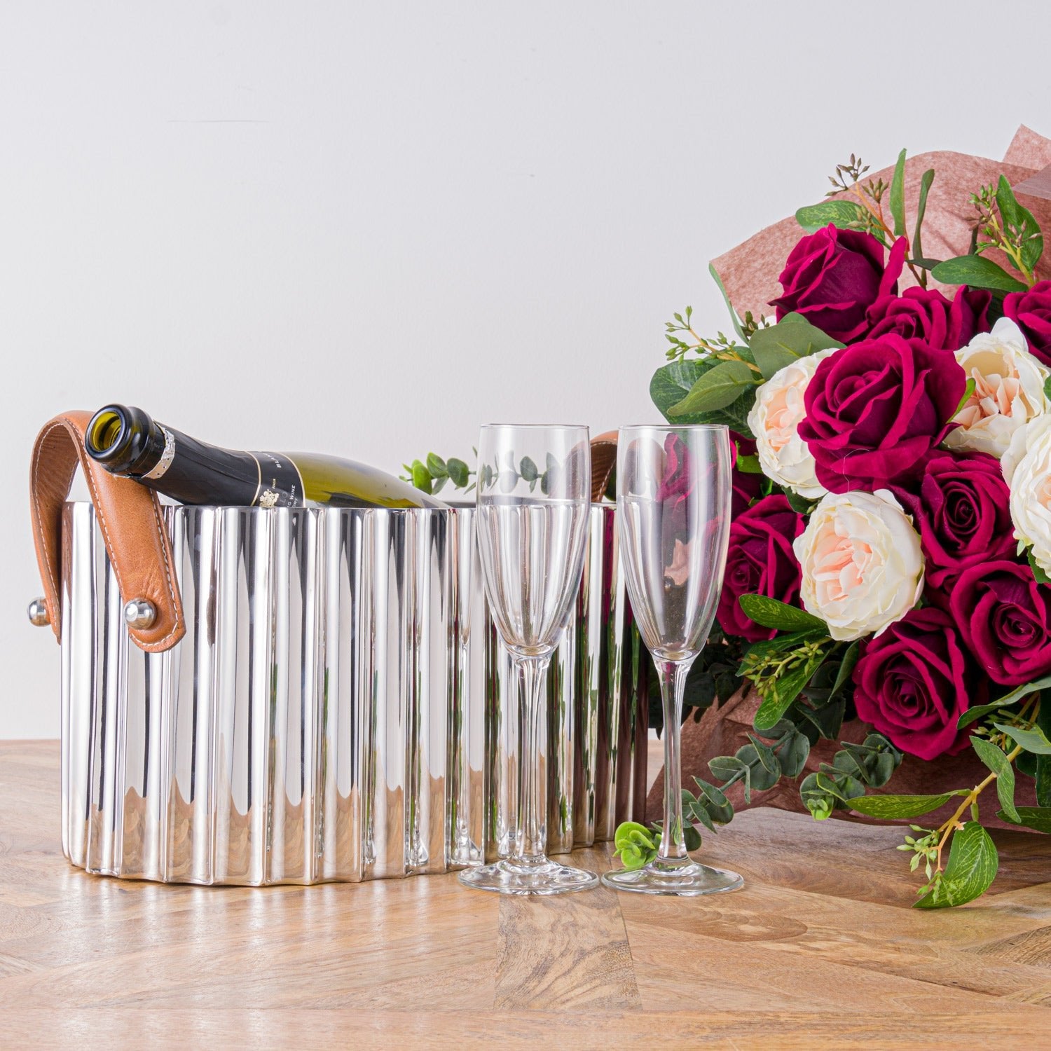 champagne bath next to two champagne glasses in front of red and pink roses