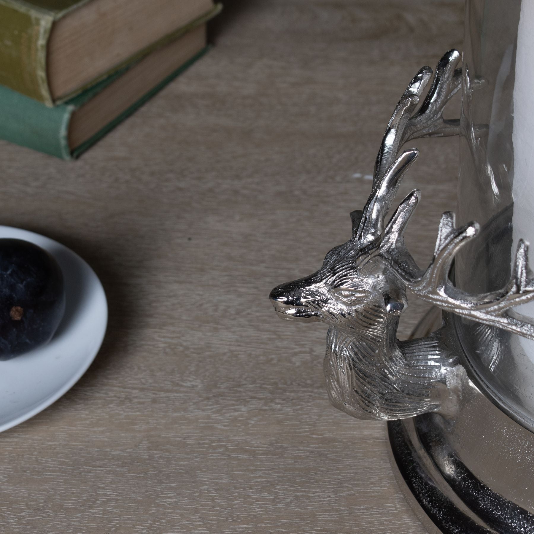 lifestyle image close up of one of the stag heads that is either side of the glass hurricane lamp